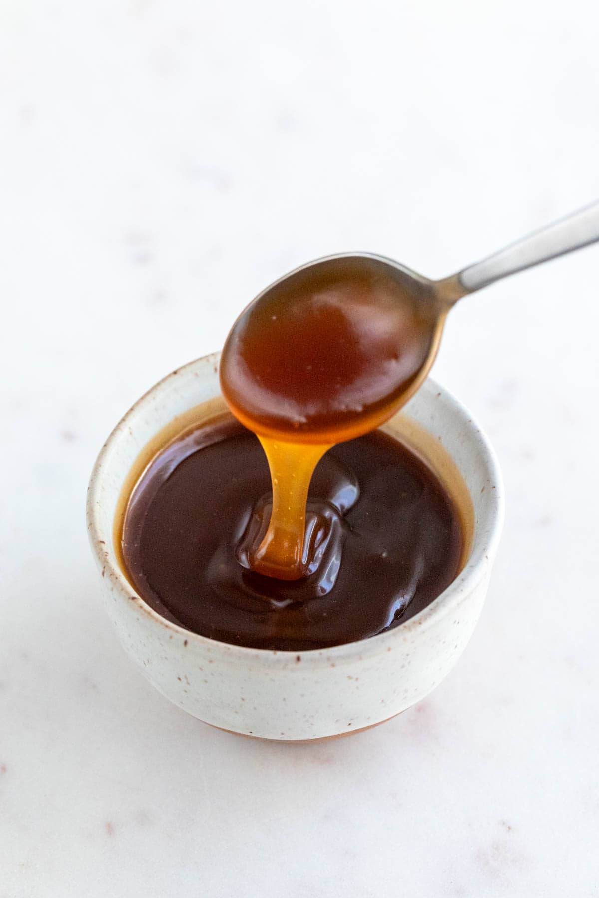 Spoon dipping into vegan caramel sauce bowl.