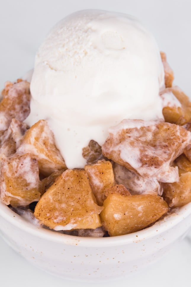 Close-up shot of a bowl of baked apples with some vegan vanilla ice cream on top