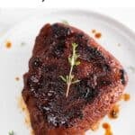 Vegan steak served on a white plate, adorned with a sprinkle of fresh thyme.