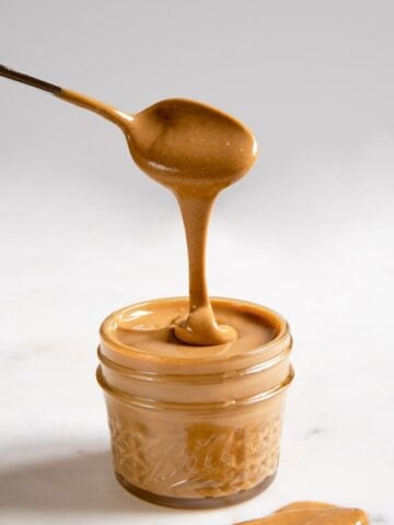 A side shot of a jar with cashew butter and a spoon