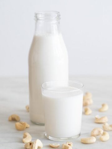 A side shot of a bottle and a glass with cashew milk
