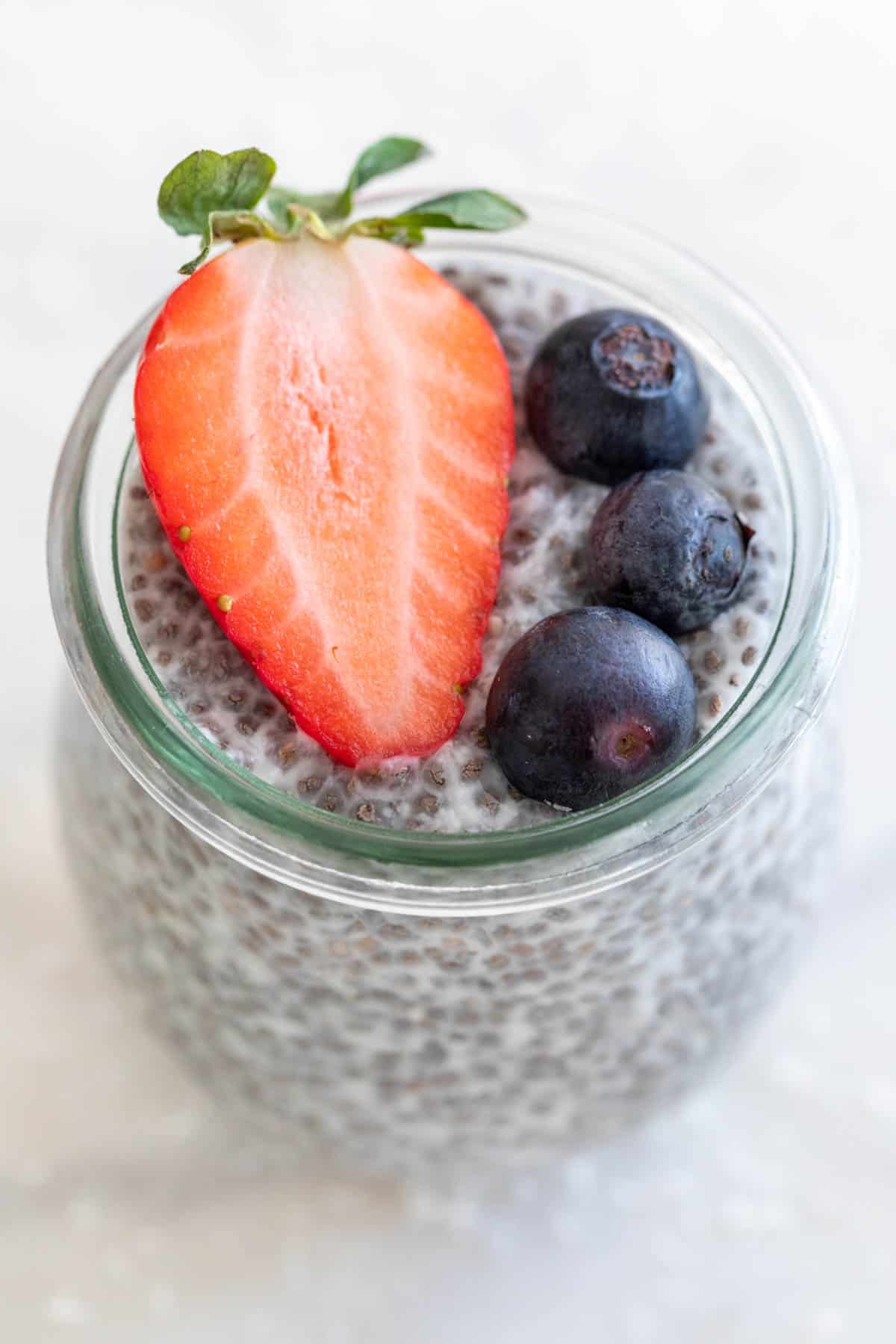 A jar of chia pudding with some berries on top.