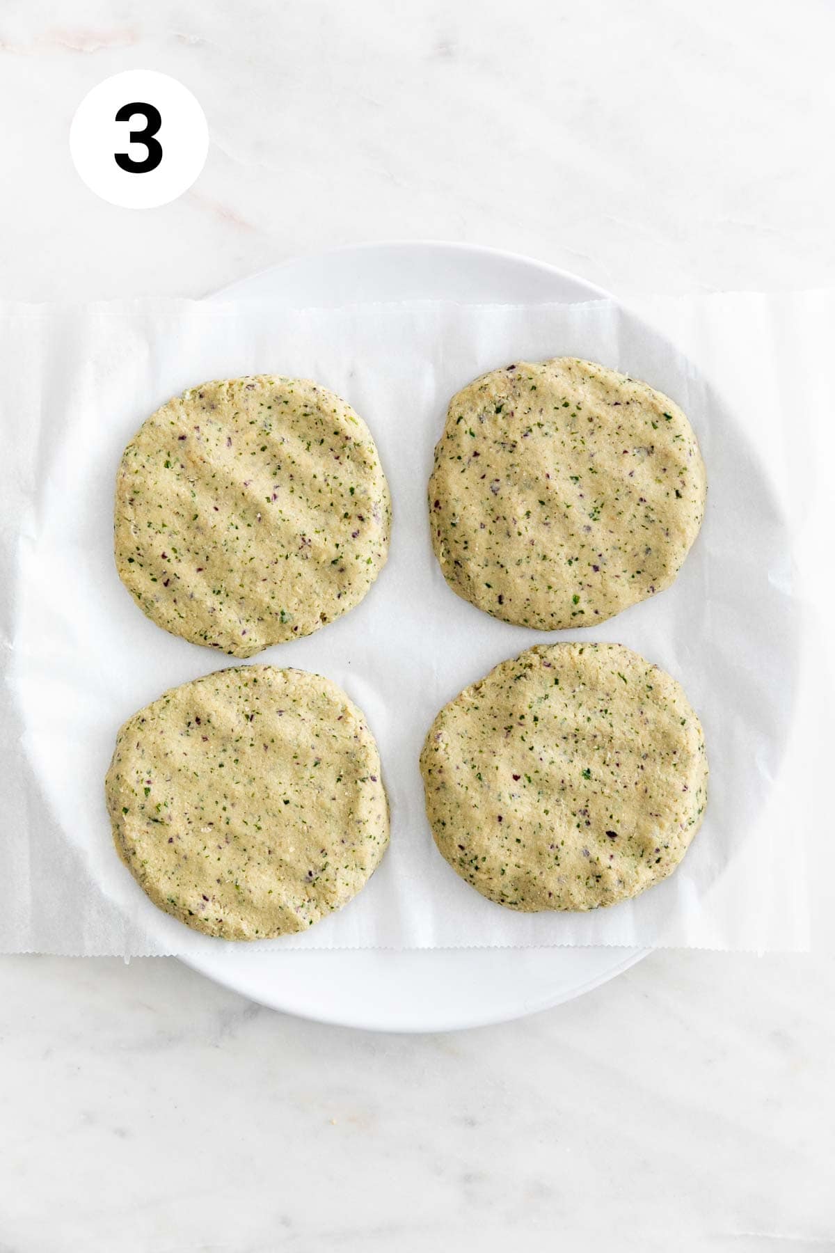 Vegan chickpea burger patties before cooking on a lined plate.
