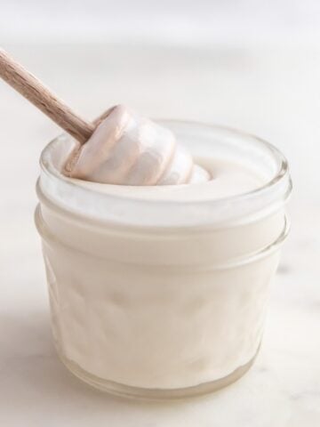 Photo of a honey dipper in a little glass of coconut butter