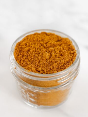 Photo of a small glass jar of curry powder