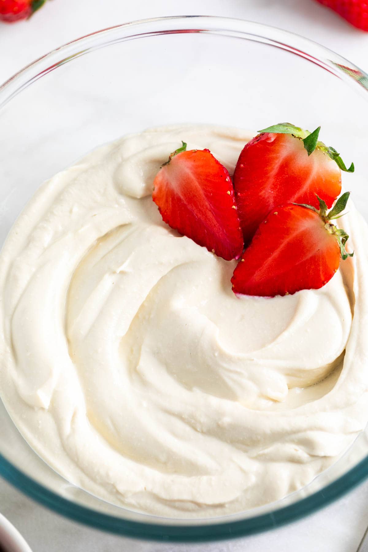 Vegan mascarpone cheese in a glass bowl with fresh strawberries.