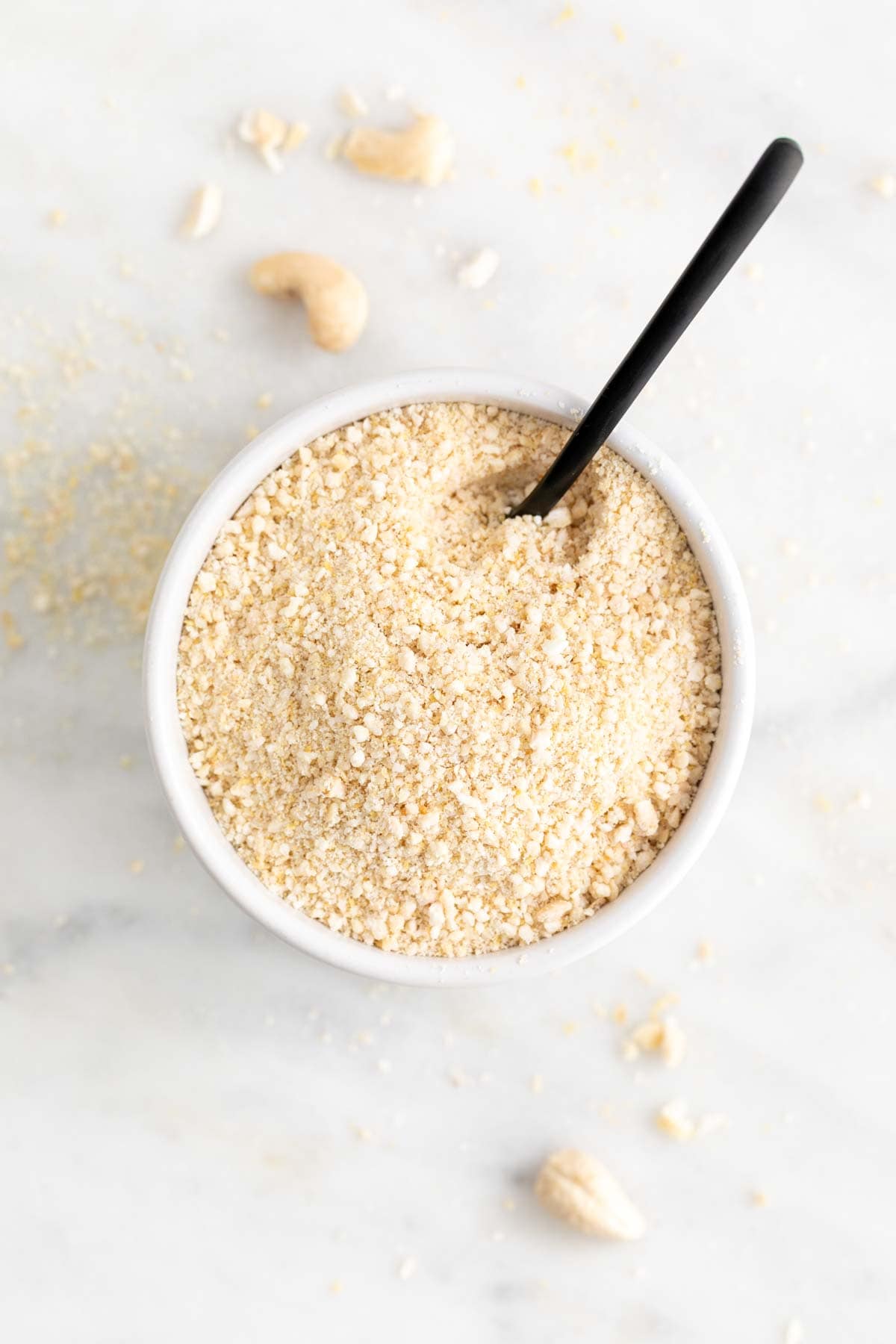 Vegan Parmesan cheese in a white bowl with a spoon.