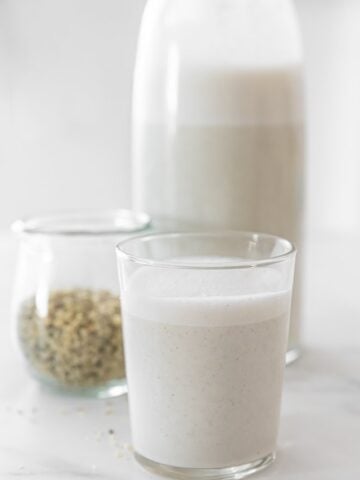 Side shot of a glas and a bottle of homemade hemp milk