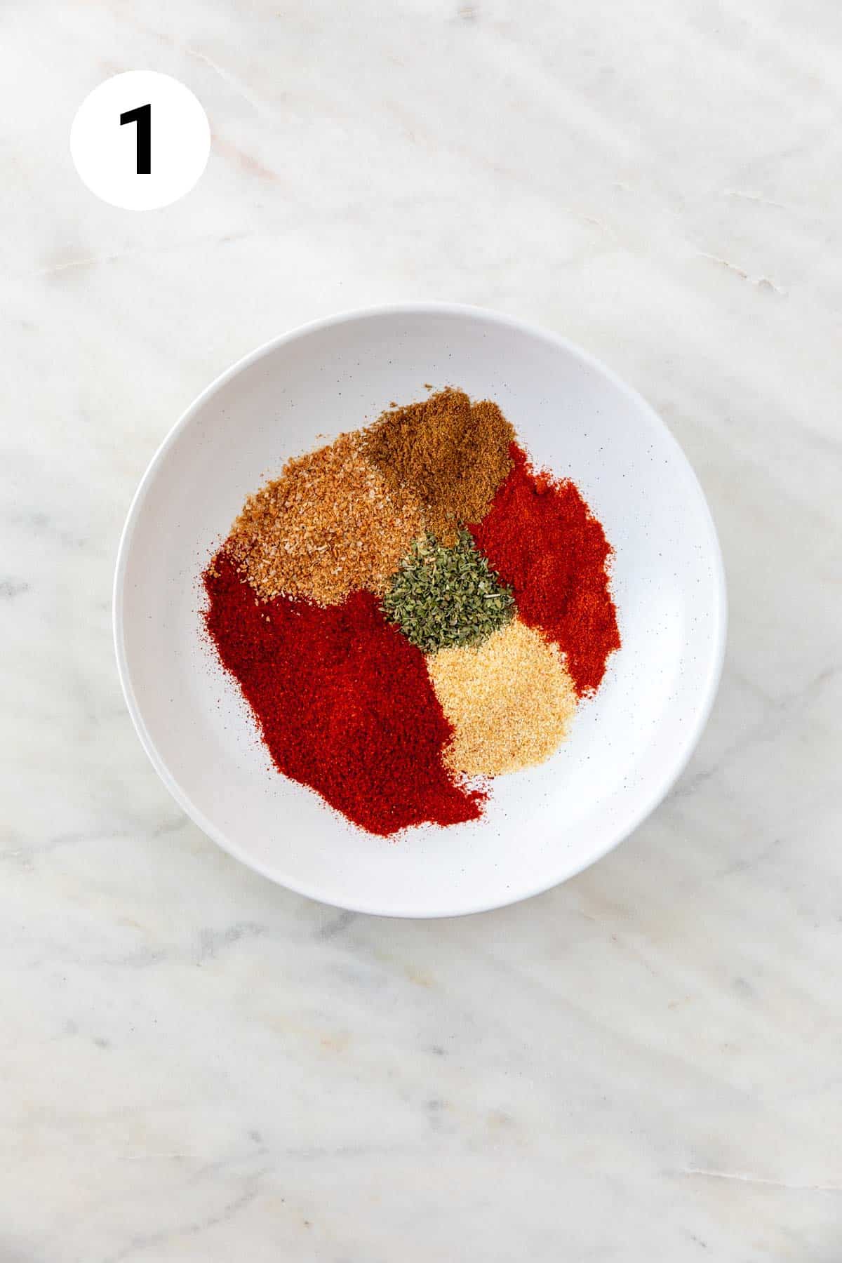 Spices needed for homemade chili powder in a shallow dish.
