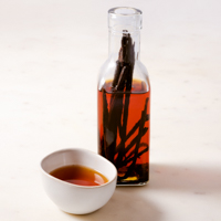 A picture of a glass botlle and a small bowl with homemade vanilla extract
