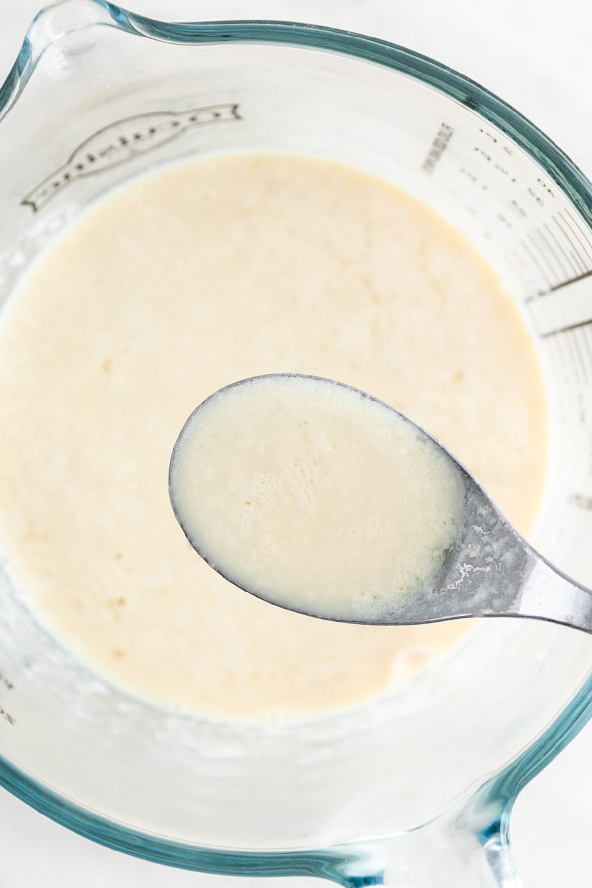 Vegan buttermilk in measuring cup with spoon.