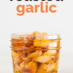 A side shot of a jar with roasted garlic cloves and covered with oil for Pinterest