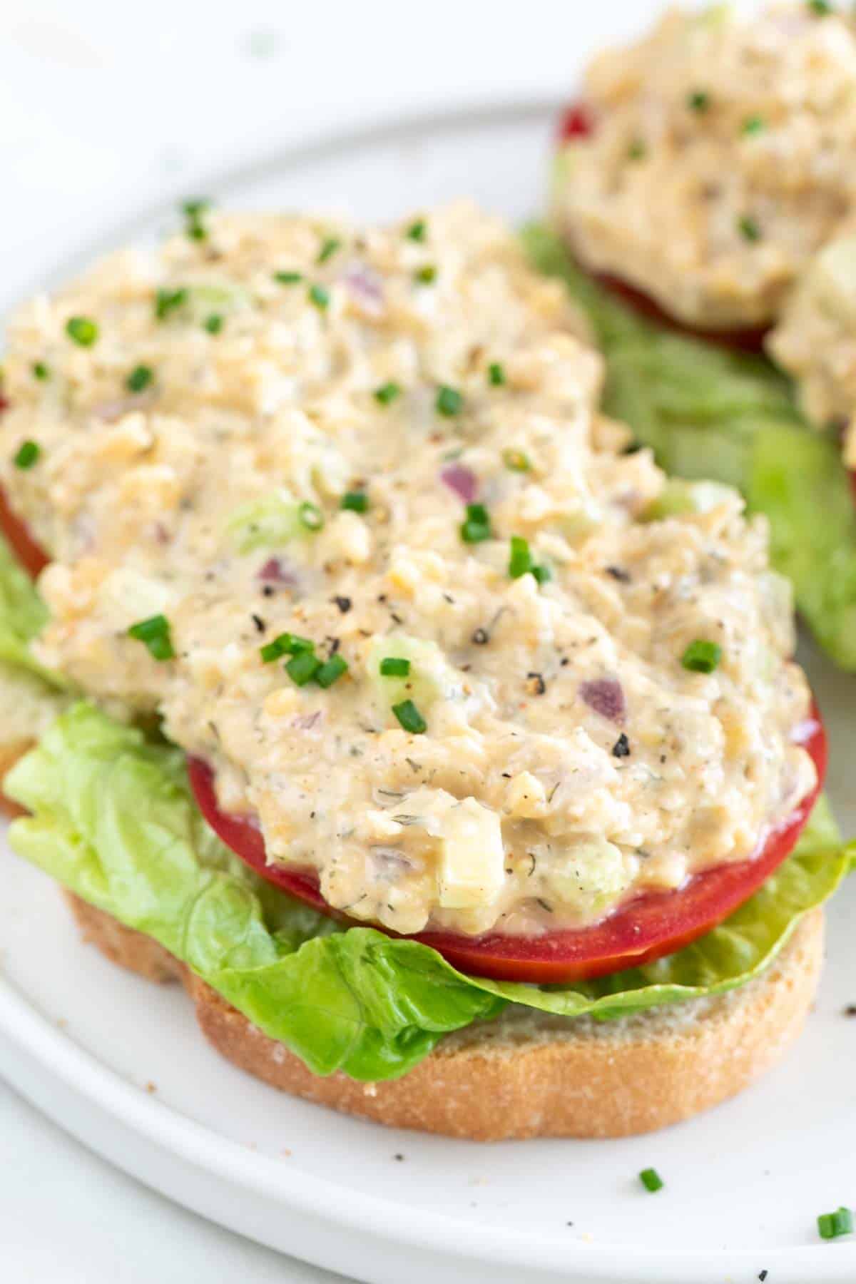 Sliced bread with lettuce, tomato, and vegan chicken salad.