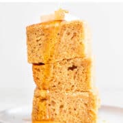 Vegan cornbread squares piled high and drizzled with vegan butter and agave syrup.