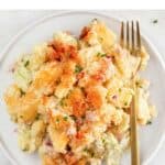 Vegan potato salad on a white plate with a golden fork.