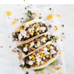 Three vegan tacos onto a white board.