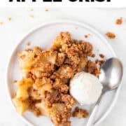 Vegan apple crisp with vegan vanilla ice cream and a spoon on a plate.