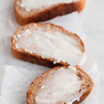Photo of some vegan butter spread onto some slices of vegan bread with a heading