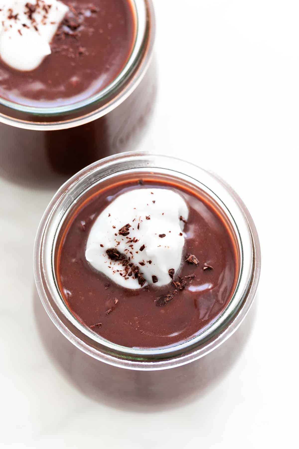 Vegan chocolate pudding in glass, garnished with whipped cream and chocolate shavings.