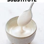 Dipping spoon into bowl of vegan heay cream substitute.