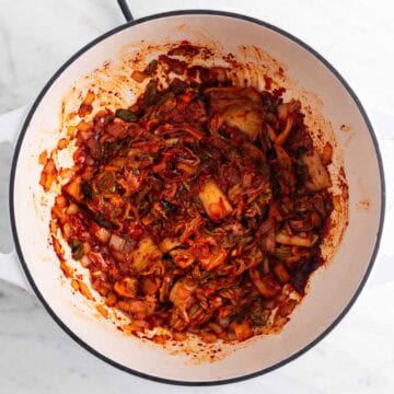 Sautéed onion, garlic, kimchi, and seasonings in a large pot.
