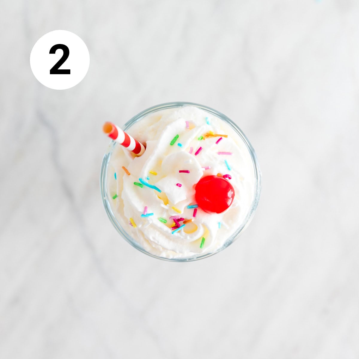 Glass of vegan ice cream decorated with toppings and a straw.