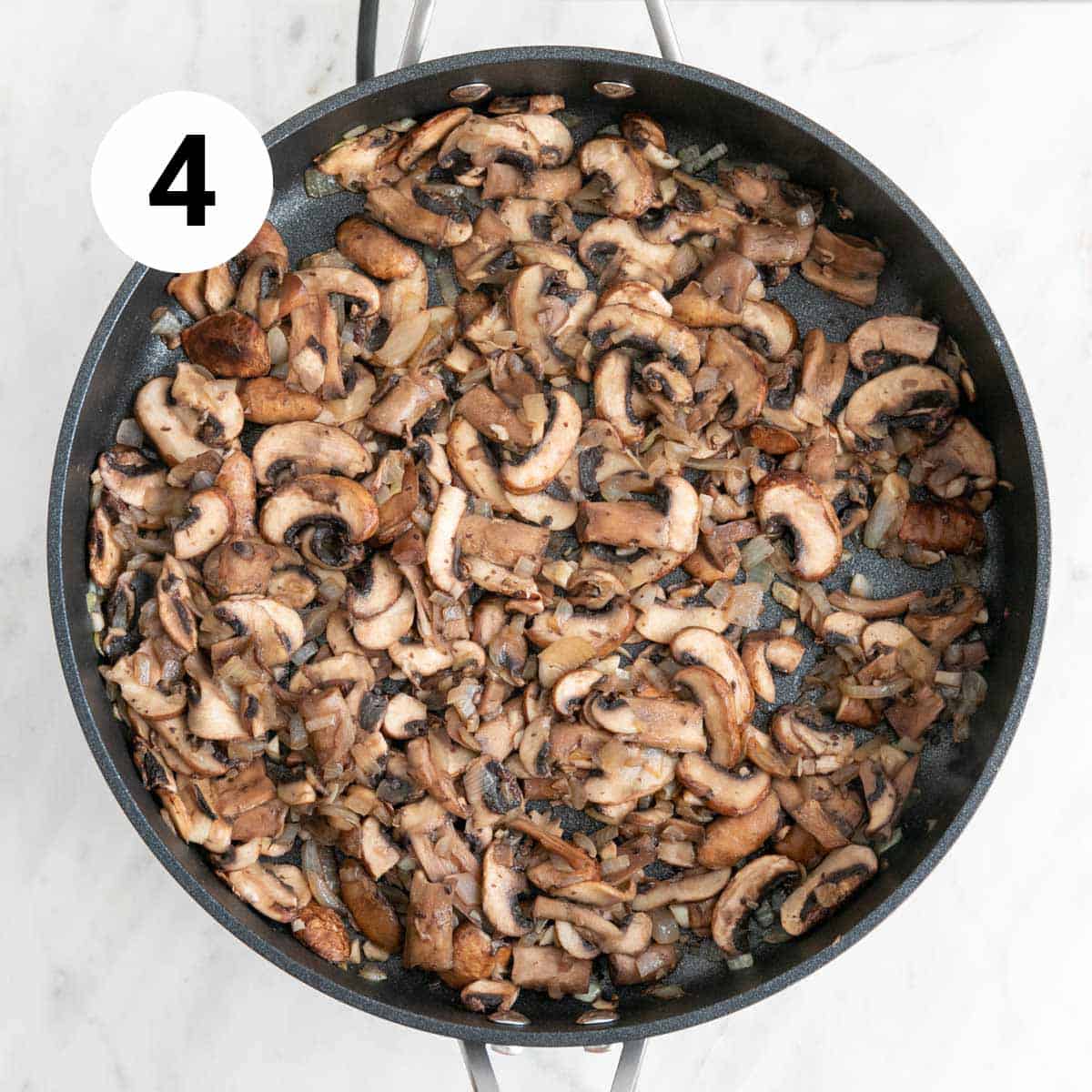 Onion, garlic, and mushrooms sautéed in a skillet.