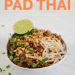 A picture of a bowl of vegan pad Thai with a sliced lime on top with the words vegan pad Thai
