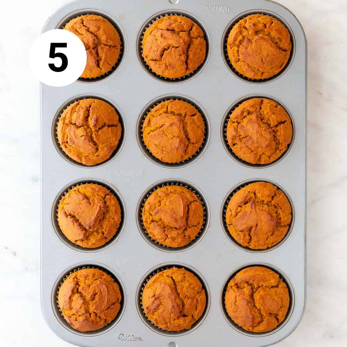 Baked vegan pumpkin muffins in a muffin pan.