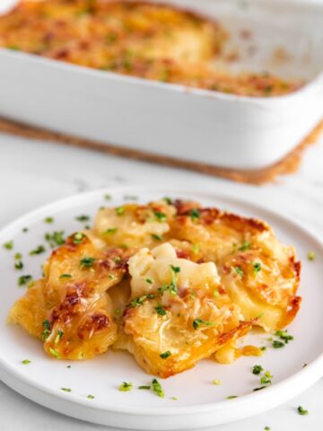 Photo of a plate and a casserole of vegan scalloped potatoes