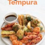A photo of a dish with homemade vegetable tempura and a small bowl with soy sauce
